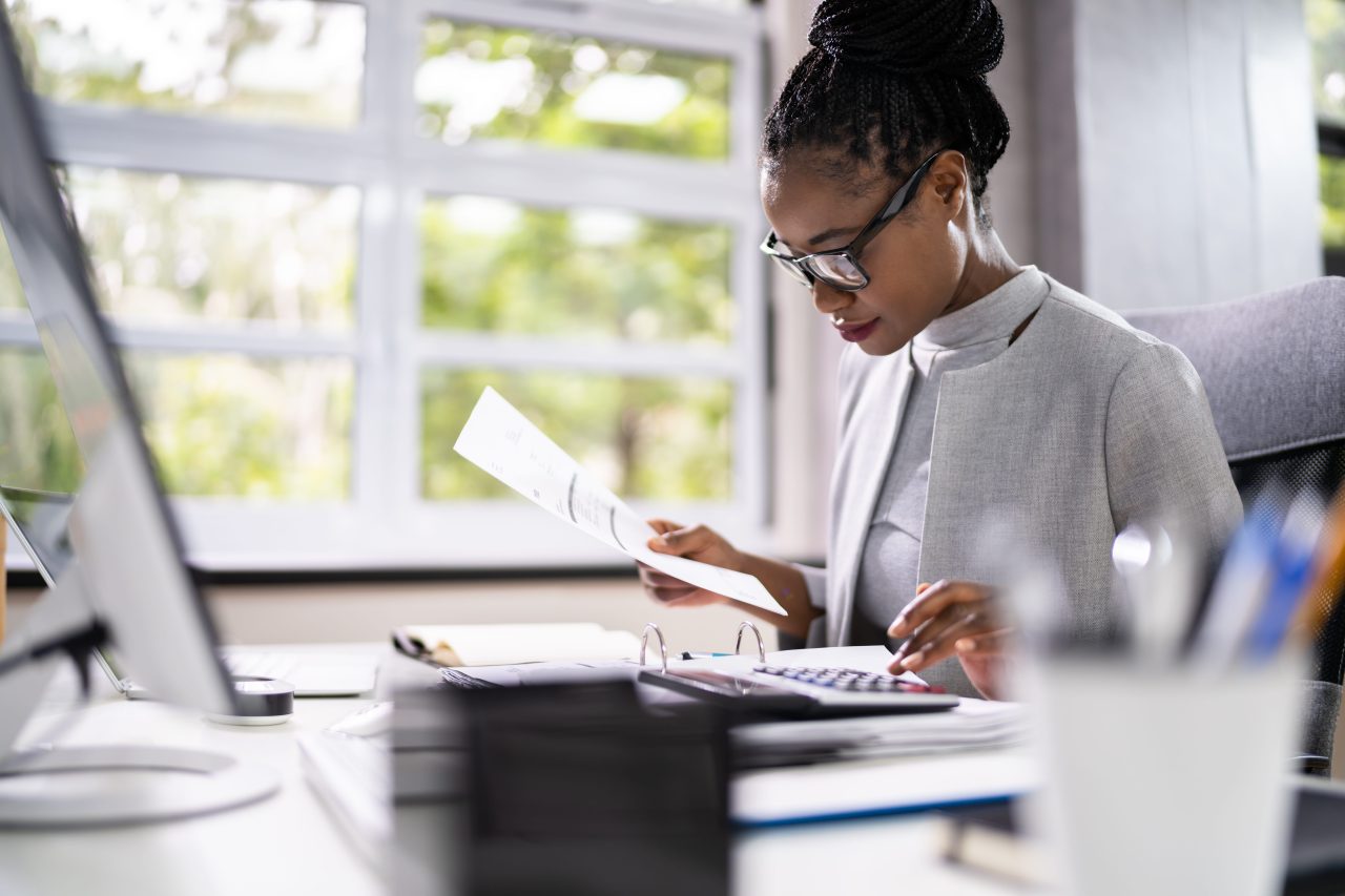 A woman wearing glasses is focused on her computer screen, engaged in work or research.